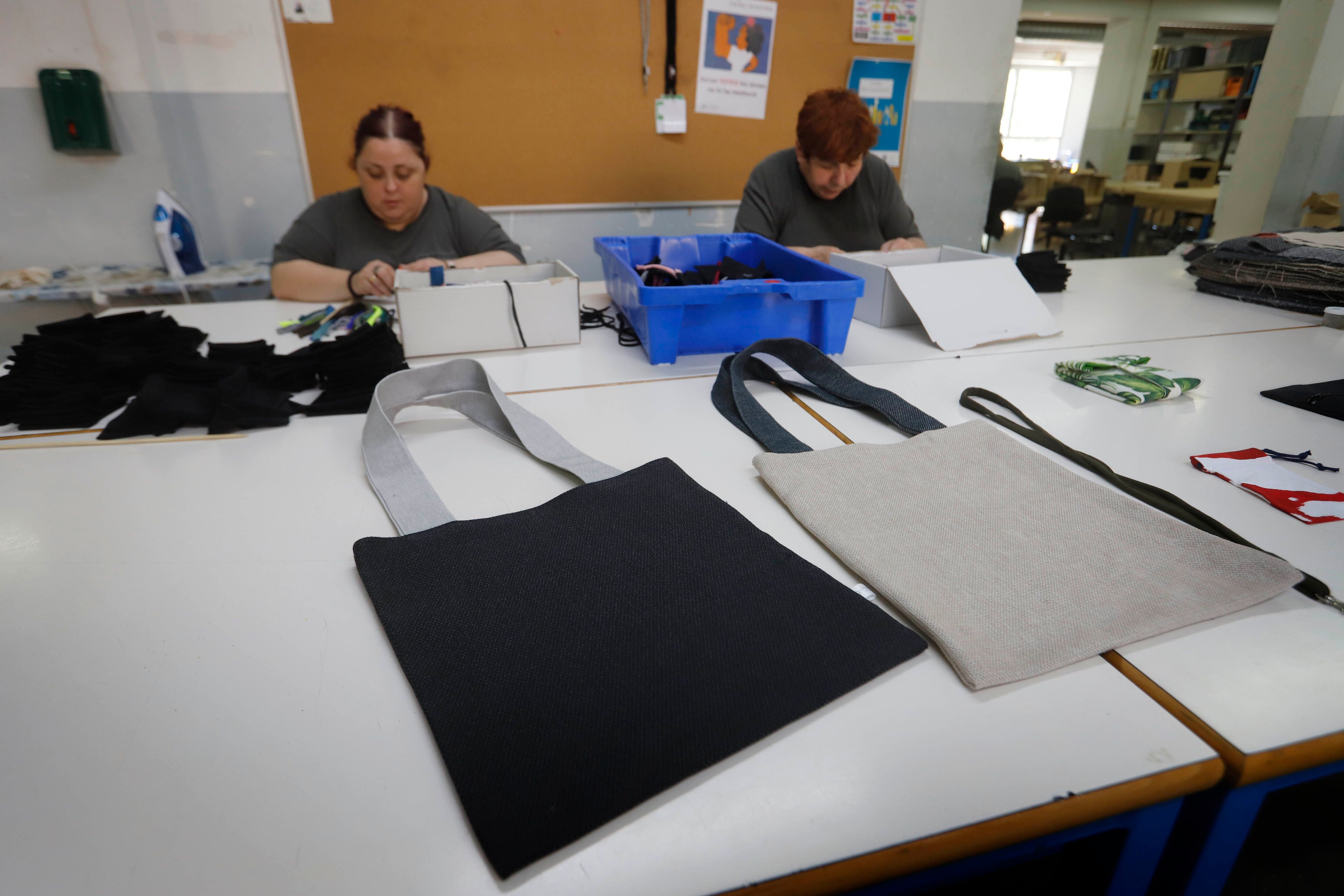 Dos trabajadoras con discapacidad fabrican bolsas de tela a partir de tejidos sobrantes en la Fundación Rubricatus, en El Prat de Llobregat (Barcelona).