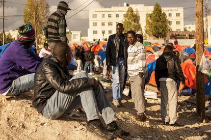 Un grupo de hombres sudaneses sentados a la entrada de la acampada. Los refugiados no tienen derecho a trabajar o disfrutar de residencia en Jordania.
