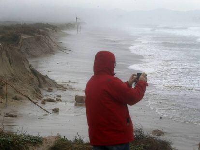 Un hombre toma imágenes de la playa de El Saler, comida por el temporal que ha obligado a la Autoridad Portuaria de Valencia a cerrar de nuevo el puerto de Valencia debido a las adversas condiciones meteorológicas.