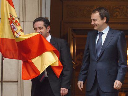 El presidente de Cantabria, Miguel Ángel Revilla, besa la bandera española junto a José Luis Rodríguez Zapatero.