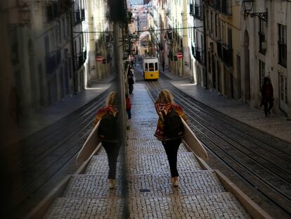 Una mujer camina con una tabla de surf por una calle de Lisboa, este viernes.