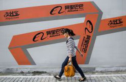 Una mujer camina junto a una pancarta publicitaria de Alibaba