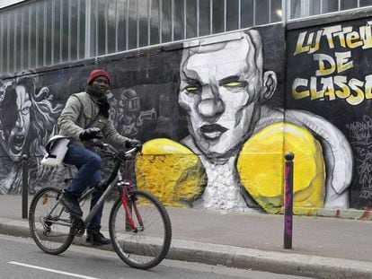 Un ciclista pasa por delante de un mural que hace referencia a las protestas de los 'chalecos amarillos'. 