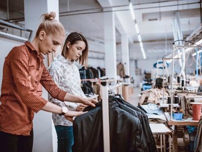 Diseñadoras de moda realizando un control de calidad en una fábrica textil.