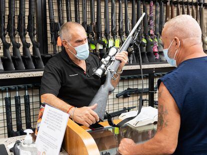 Un vendedor de armas muestra un rifle a un cliente en una tienda de Nueva York durante la pandemia.