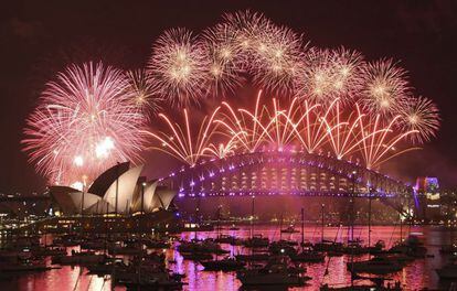 Un espectáculo de fuegos artificiales ilumina el cielo sobre el Teatro de la Ópera y el puente Harbour.