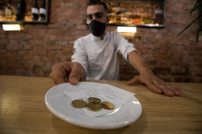 Un camarero recoge una propina en metálico.