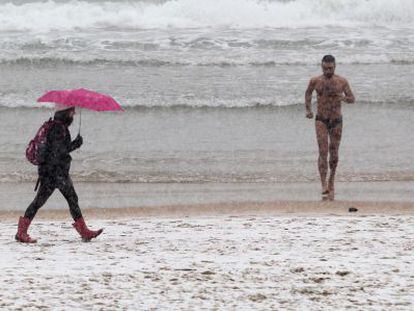 Un hombre en bañador corre por una nevada playa de la Concha, en San Sebastián.
