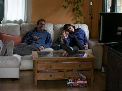 Una familia viendo la televisión en el salón de su casa.