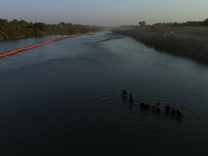 Migrantes pasan una serie de boyas en la orilla del río Grande para entrar a los Estados Unidos desde México.
