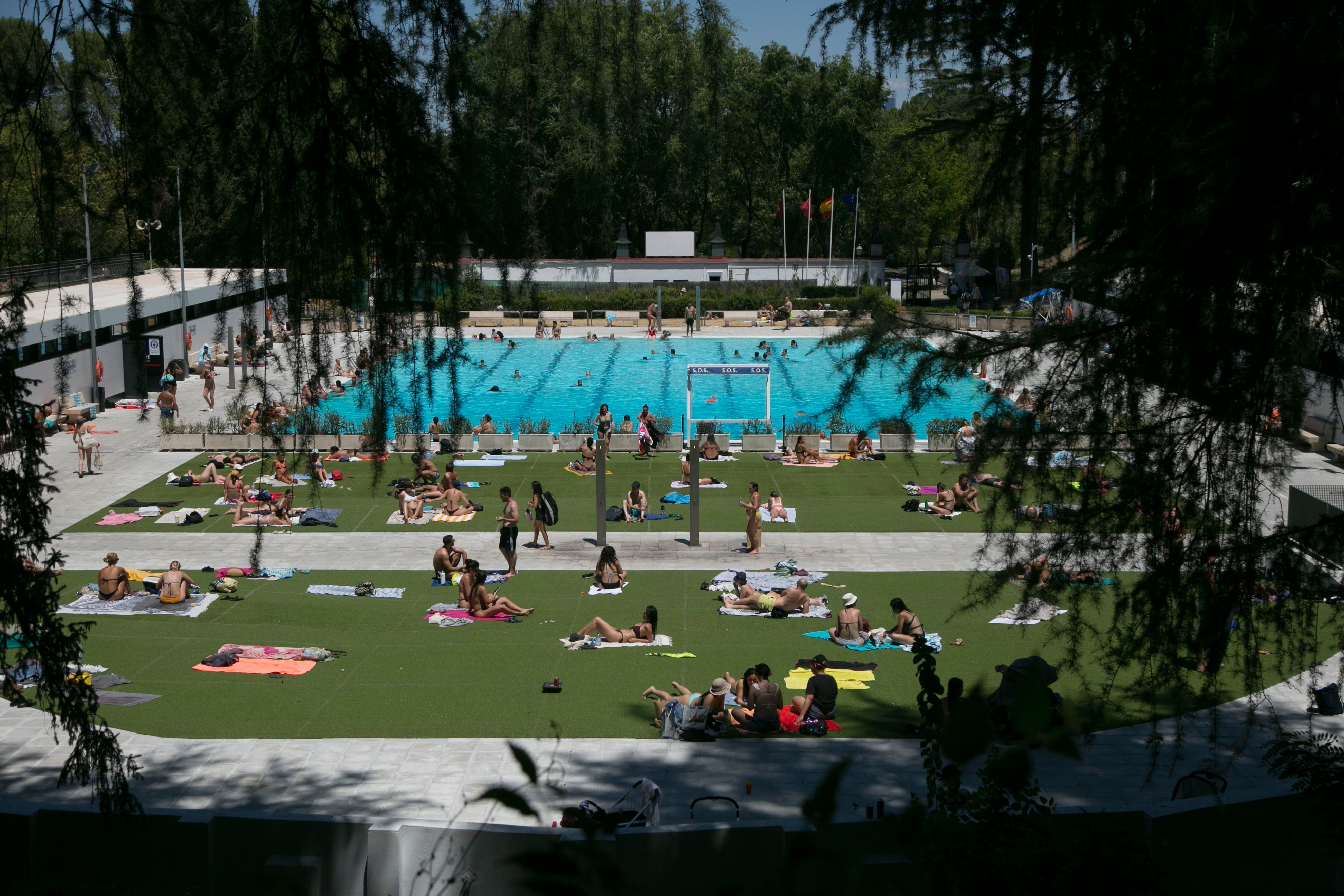 Vista de varias personas disfrutando de la piscina municipal de El Lago, en Casa de campo (Madrid) en julio de 2023.