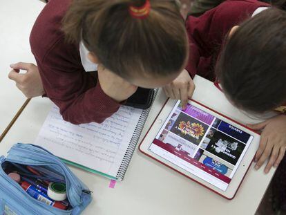 Dos niñas trabajan en clase con una tableta.