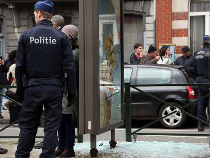 Un polic&iacute;a vigila al lado de un cristal roto por una explosi&oacute;n controlada, durante una redada en el barrio bruselense de Schaerbeek.