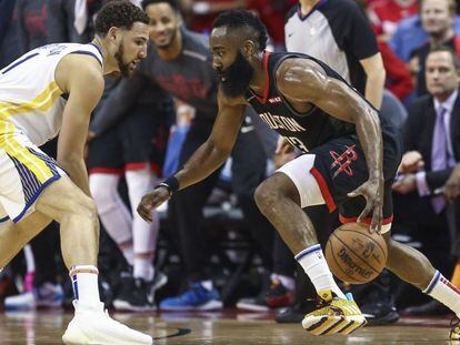 Klay Thompson trata de frenar a Harden.  