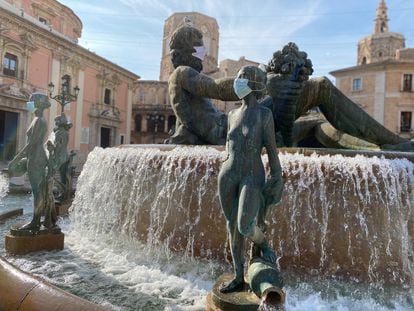 Las estatuas de la Fuente de Neptuno, en la plaza de la Virgen de Valencia, han amanecido con mascarilla.