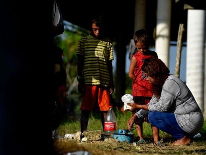 Una mujer de la caravana de migrantes con destino a Estados Unidos cocina en presencia de unos niños en Palo Dulce, estado de Veracruz, México, el 17 de noviembre de 2021.