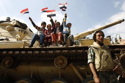Cuatro niños levantan banderas subidos a un blindado del Ejército egipcio en la plaza de la Liberación.