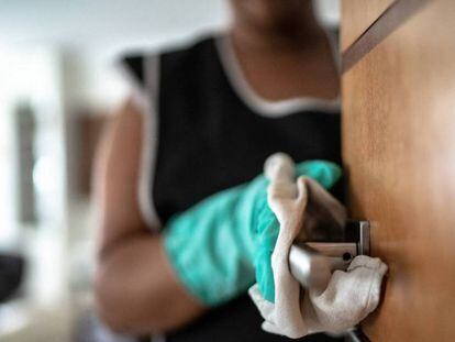  Una trabajadora doméstica limpia la puerta de un hogar. GETTY