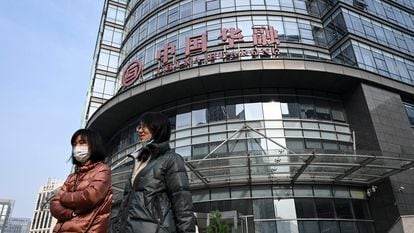 Dos mujeres caminan frente a un edificio de Huarong, en Pekín, este jueves.