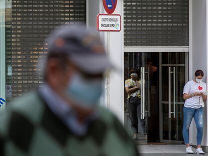 Una empleada consulta su móvil ante la reja a medio abrir de una tienda de ropa en Sevilla hoy jueves, día en el que algunos comercios de la ciudad empiezan a preparar su reapertura durante el proceso de desescalada.