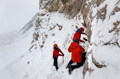 Un explorador militar observa a los científicos chilenos Nicolás Bruna (2-d) y Matías Vargas (d) mientras recogen muestras de sedimentos en el valle Elephant Head en el Glaciar Unión, situado en las montañas Ellsworth, en la Antártida, el 21 de noviembre de 2018.