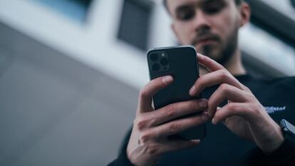 Un hombre mira un teléfono móvil.
