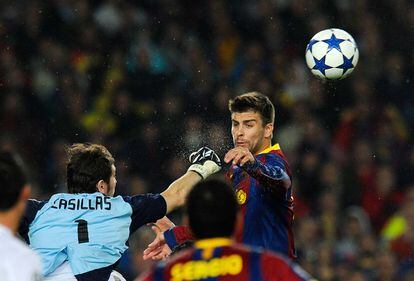 El portero del Madrid Iker Casillas (a la izquierda) despeja el balón de puños ante el acoso de Piqué, en un Clásico de 2011.