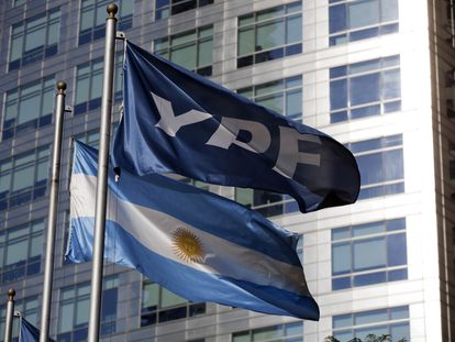 Una bandera nacional argentina junto a la de la compañía YPF.