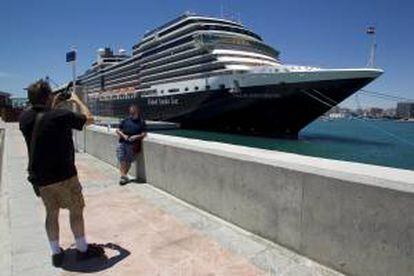 Dos pasajeros del crucero para homosexuales "Nieuw Amsterdam" se fotografían ante dicho barco, que ha atracado esta mañana en el puerto de Málaga después de que las autoridades marroquíes prohibieran la escala que tenía prevista para hoy en Casablanca.