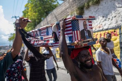 Manifestantes cargan un ataúd con una foto del primer ministro de Haití, y las banderas de Estados Unidos y Canadá durante una protesta para exigir la renuncia de Henry y rechazar la propuesta de intervención extranjera.