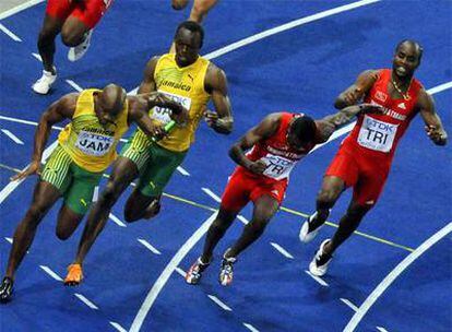 Usain Bolt entrega el testigo a Asafa Powell, a la izquierda, por delante de los atletas de Trinidad y Tobago.