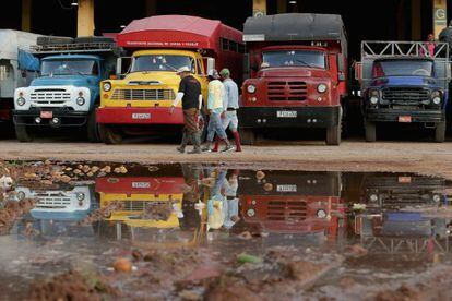 Un grupo de trabajadores pasan ante unos camiones, en La Habana.