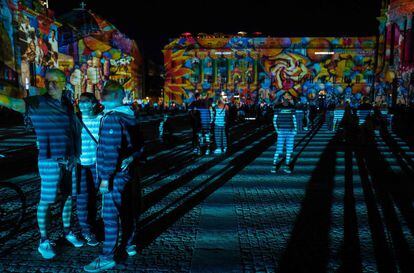 Un grupo de personas visitan la Bebel platz iluminada como parte del Festival de las Luces anual en Berlín (Alemania).