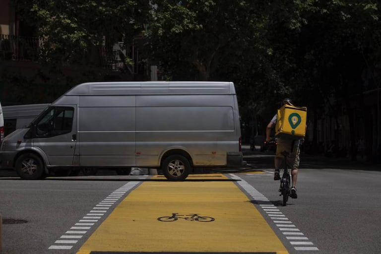 Un repartidor de Glovo y una furgoneta en el nuevo carril bici de Pau Claris.
