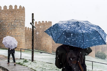 Dos personas pasean junto a la muralla de Ávila este viernes, bajo la nieve.