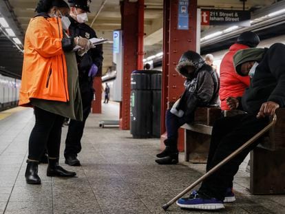 Un trabajador social y un policía atienden a un hombre en un andén del metro de Nueva York, en 2020.
