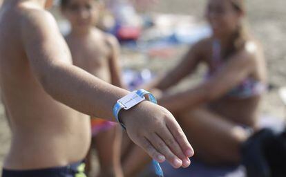 Un ni&ntilde;o muestra su pulsera en una playa de Castell&oacute;n.