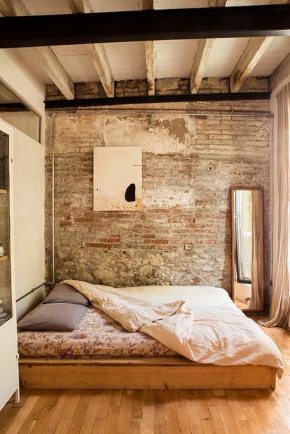 Sencillez absoluta en el dormitorio con una estructura de cama diseñada por ellos y cuadro de piedra de Turbina.