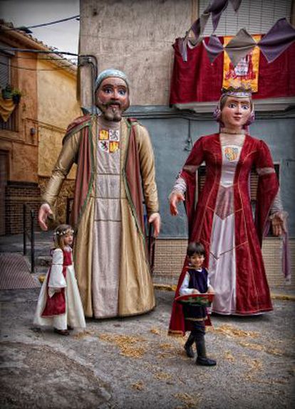 Dos niños pasan delante de dos gigantes durante un pasacalles en las Fiestas del Medievo de Villena (Alicante).