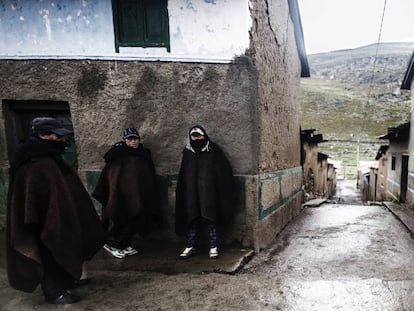 Tres hombres se protegen del frío en los Andes peruanos.