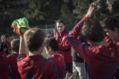 Sergi Ayuso, técnic de l'equip infantil del CP Sarrià, envoltat per alguns dels seus jugadors al camp de Can Caralleu.