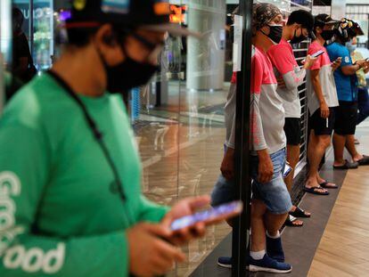 Repartidores de comida esperan pedidos en un centro comercial de Singapur.
