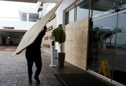 Un trabajador cubre las ventanas y los paneles de vidrio de un hotel frente al mar de Mazatlán, en el Estado de Sinaloa.