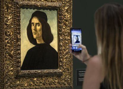 Una mujer toma una imagen del 'Retrato de Michele Marullo Tarcaniota', de Sandro Botticelli, que ha sido presentado este martes en el Museo de Bellas Artes de Valencia.