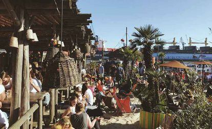 Terraza del bar de playa StrandPauli, en Hamburgo, con las grúas del puerto al fondo.