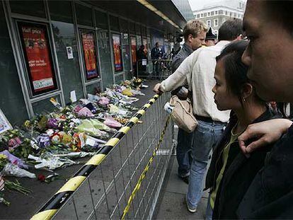 La gente observa los improvisados tributos florales dejados en las afueras de la estación de King's Cross.