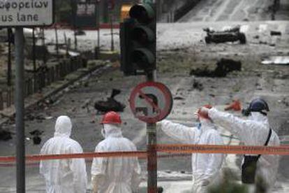 Artificieros recogen pruebas en el lugar donde hoy se ha producido la explosión de un coche bomba en el centro de Atenas (Grecia).