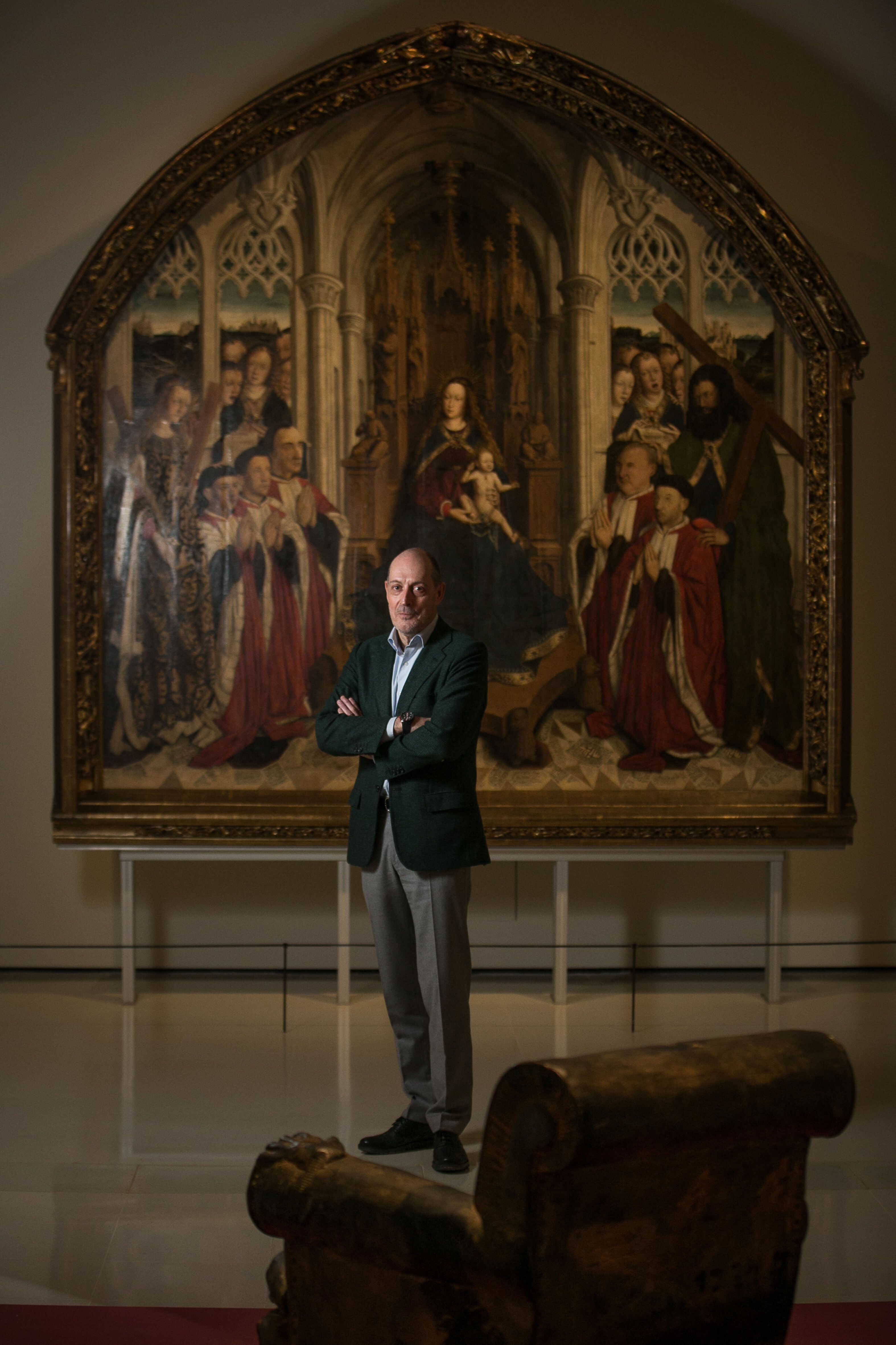 Joan Oliveras entre el sillón creado por Tàpies y la obra gótica de Dalmau que puede verse dentro de la exposición 'Intrusos' del MNAC, el museo que él preside.
