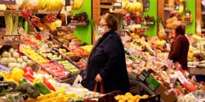 Una mujer compra en un puesto de frutas y verduras.