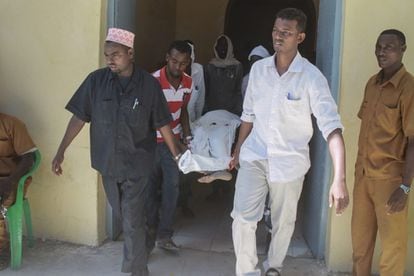 Un grupo de hombres traslada a la v&iacute;ctima de un atentado de Al Shabab en Mogadiscio este jueves. 